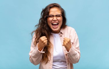 Sinirli, hayal kırıklığına uğramış, kızgın bakışlar ve sıkı yumruklarla bağıran bir kadın.