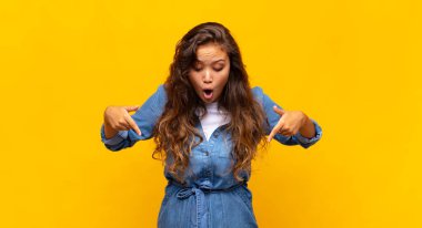 Kadın şok olmuş, ağzı açık ve şaşkın, inançsızlık ve şaşkınlık içinde bakıyor ve onu işaret ediyor.