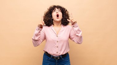 Kadın şaşırmış, şaşırmış ve ağzı açık bir şekilde iki eliyle uzayı işaret ediyor.