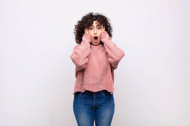 Kadın mutsuz, korkmuş ya da endişeli görünüyor, ağzı sonuna kadar açık ve iki kulağını da elleriyle kapatıyor.