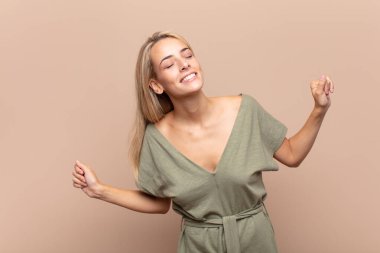 Gülümseyen, kaygısız, rahat ve mutlu hisseden, dans eden ve müzik dinleyen, bir partide eğlenen bir kadın.