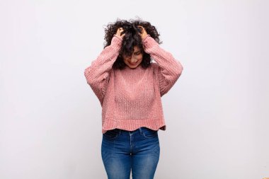 Kadın kendini stresli ve hayal kırıklığına uğramış hissediyor, el ele tutuşuyor, yorgun, mutsuz ve migren ağrısı çekiyor.