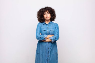 Kadın mutsuz ve hayal kırıklığına uğramış, ciddi görünüyor, sinirlenmiş ve kollarını kavuşturmuş.