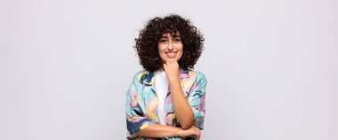 Mutlu görünen ve gülümseyen bir kadın, merak eden ya da soru soran, seçenekleri karşılaştıran.