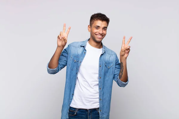 stock image  smiling and looking happy, friendly and satisfied, gesturing victory or peace with both hands