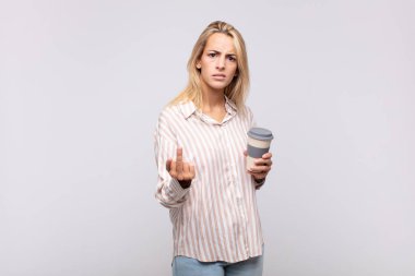 Kahve içen genç bir kadın kızgın, sinirli, isyankar ve agresif orta parmağını sallayarak karşılık veriyor.