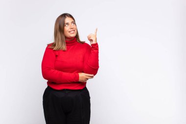 Genç sarışın kadın mutlu bir şekilde gülümsüyor ve yan bakıyor, merak ediyor, düşünüyor ya da bir fikri var.