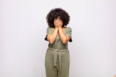 Üzgün, hayal kırıklığına uğramış, gergin ve depresif hisseden bir kadın. İki eliyle yüzünü kapatıyor, ağlıyor.
