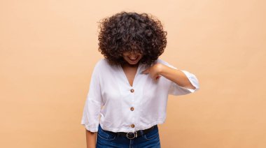 Neşeli bir şekilde gülümseyen, aşağıya bakan ve göğsünü gösteren bir kadın.