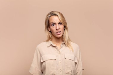 Woman feeling puzzled and confused, with a dumb, stunned expression looking at something unexpected