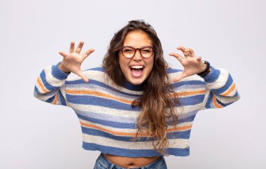 Kadın panik ya da öfke içinde bağırıyor, şok olmuş, korkmuş ya da öfkeli, elleri başının yanında.