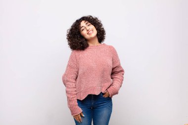 Kadın neşeli bir şekilde gülümsüyor, pozitif, mutlu, kendine güvenen ve rahat bir ifadeyle.