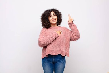 Mutlu, kendinden emin, güvenilir, gülümseyen ve zafer işareti gösteren bir kadın.