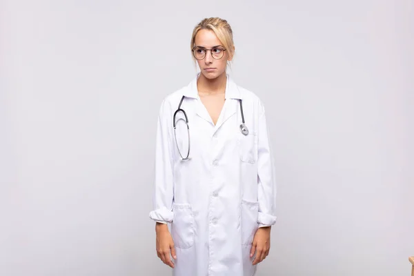 若い女性医師は悲しい 動揺や怒りを感じ 否定的な態度で側を見て 意見の相違に眉をひそめて — ストック写真