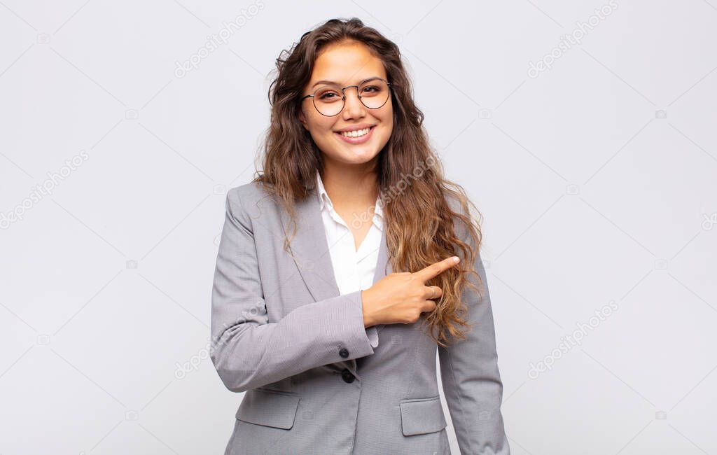 Woman smiling cheerfully, feeling happy and pointing to the side and upwards, showing object in copy space