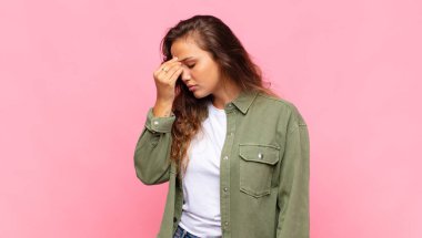 Stresli, mutsuz ve hayal kırıklığına uğramış hisseden, alnına dokunan ve şiddetli baş ağrısı çeken bir kadın.