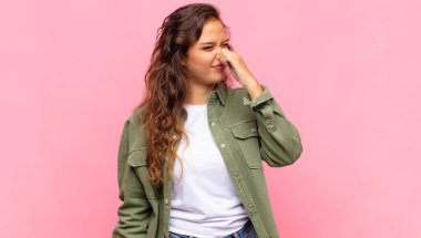 Kadın iğreniyor, pis ve nahoş bir koku duymamak için burnunu tutuyor.