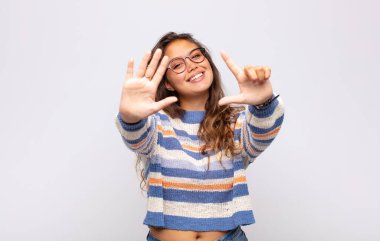 Gülümseyen ve arkadaş canlısı görünen bir kadın, 7 ya da 7 numarayı gösteriyor, eli önde, geriye doğru sayıyor.