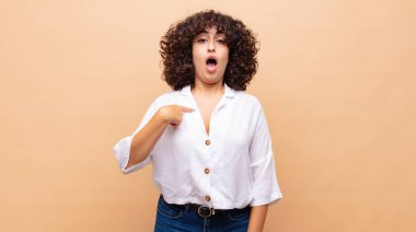 Şok olmuş ve ağzı açık, kendini işaret eden bir kadın.