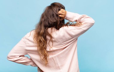 Kadın kendini cahil ve kafası karışık hissediyor, bir çözüm düşünüyor, eli kalçasında, diğeri kafasında, dikiz aynasından.