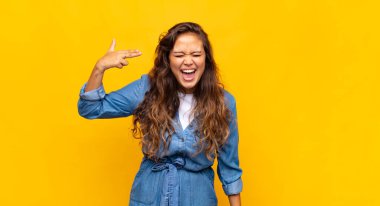 Kadın mutsuz ve stresli görünüyor, intihar jesti elle silah işareti yapıyor, kafasını işaret ediyor.