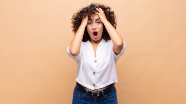 Kadın dehşete kapılmış ve şok olmuş hissediyor, ellerini havaya kaldırıyor ve hata yaptığında panikliyor.