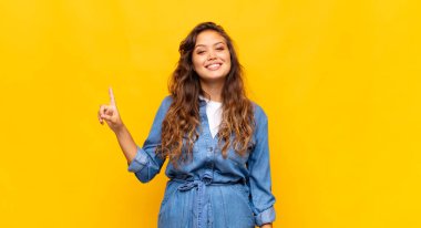 Neşeli ve mutlu bir şekilde gülümseyen bir kadın, tek eliyle boşluğu dolduruyor.