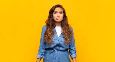 Şaşırmış ve kafası karışmış bir kadın, gergin bir hareketle dudağını ısırıyor, sorunun cevabını bilmiyor.