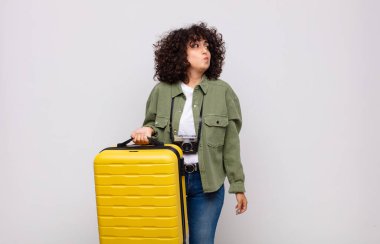 Genç Arap kadın omuz silkiyor, kafası karışık ve kararsız, kolları bağlı ve şaşkın görünüyor seyahat konsepti