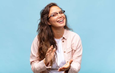 Kadın kendini mutlu ve başarılı hissediyor, gülümsüyor ve alkışlıyor, alkışlarla tebrik ediyor.