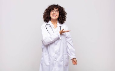 Genç kadın doktor mutlu bir şekilde gülümsüyor, kendini mutlu hissediyor ve fotokopi alanında bir konsept gösteriyor.