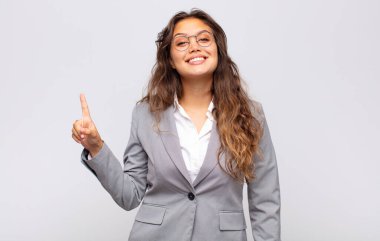 Neşeli ve mutlu bir şekilde gülümseyen bir kadın, tek eliyle boşluğu dolduruyor.