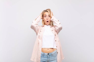 Kadın heyecanlı ve şaşırmış görünüyor, ağzı açık, elleri başının üstünde, şanslı bir kazanan gibi hissediyor.