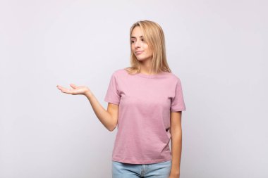 Kadın kendini mutlu hissediyor ve gelişigüzel gülümsüyor. Elinde tuttuğu bir nesneye ya da konsepte bakıyor.