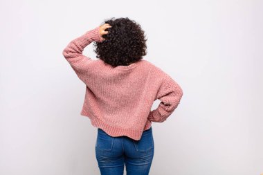 Kadın kendini cahil ve kafası karışık hissediyor, bir çözüm düşünüyor, eli kalçasında, diğeri kafasında, dikiz aynasından.