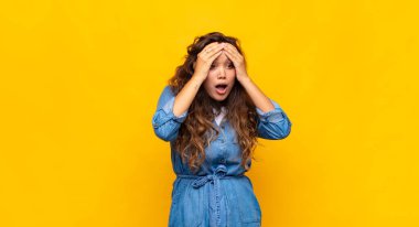 Kadın dehşete kapılmış ve şok olmuş hissediyor, ellerini havaya kaldırıyor ve hata yaptığında panikliyor.