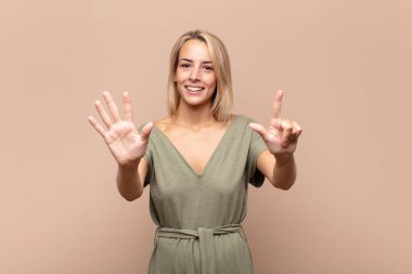 Gülümseyen ve arkadaş canlısı görünen bir kadın, 7 ya da 7 numarayı gösteriyor, eli önde, geriye doğru sayıyor.