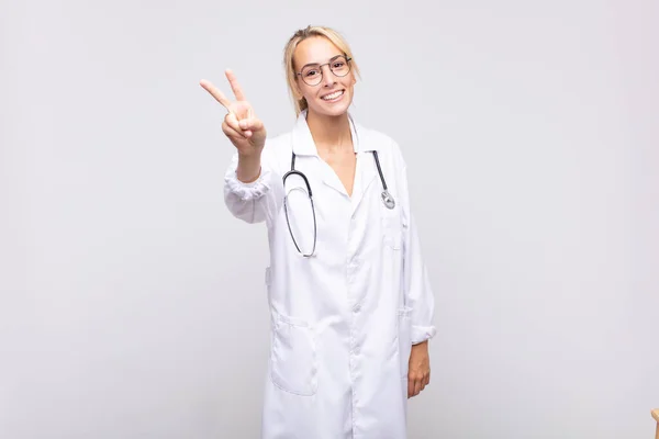若い女性医師は笑顔で幸せそして気楽でポジティブで勝利や平和を片手に — ストック写真