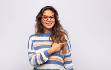 Neşeli bir şekilde gülümseyen, mutlu hisseden, kenarı ve yukarıyı gösteren, fotokopi alanında nesneler gösteren bir kadın.