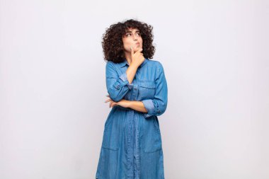 Kadın düşünüyor, kuşkulu ve şaşkın hissediyor, farklı seçeneklerle, hangi kararı vereceğini merak ediyor.