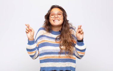 Kadın gülümsüyor ve endişeyle parmaklarını çaprazlıyor, endişeli ve iyi şanslar diliyor.