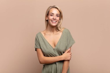 Kadın utangaç ve neşeli bir şekilde gülüyor, arkadaş canlısı ve olumlu ama güvensiz bir tavırla.