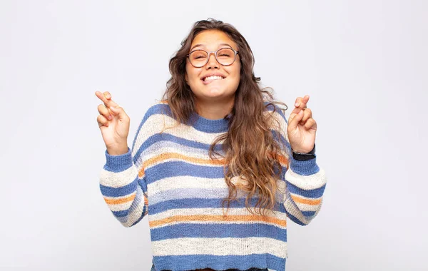 Kadın gülümsüyor ve endişeyle parmaklarını çaprazlıyor, endişeli ve iyi şanslar diliyor.