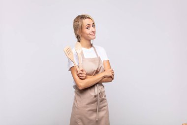 Genç kadın şef omuz silkiyor, kafası karışık ve emin değil, kolları bağlı ve şaşkın görünüyor.