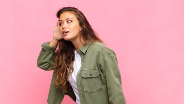 Gülümseyen bir kadın, tuhaf bir şekilde yan tarafa bakıyor, dedikoduları dinlemeye ya da bir sırrı duymaya çalışıyor.