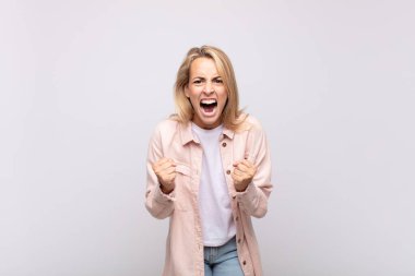 Sinirli, hayal kırıklığına uğramış, kızgın bakışlar ve sıkı yumruklarla bağıran bir kadın.