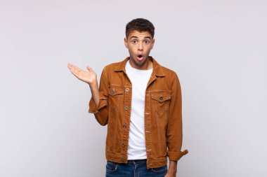  Şaşırmış ve şoke olmuş bir halde, çenesi düşmüş bir objeyi elinde açık bir elle tutarken.