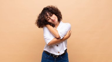 Aşık olan, gülümseyen, kendine sarılan, yalnız kalan, bencil ve benmerkezci bir kadın.