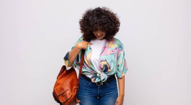 Neşeli bir şekilde gülümseyen, aşağıya bakan ve göğsünü gösteren bir kadın.