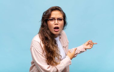 Kadın şaşkın ve şaşırmış hissediyor, yan taraftaki fotokopi alanını işaret ediyor, şaşkın, açık ağızlı bir bakışla.